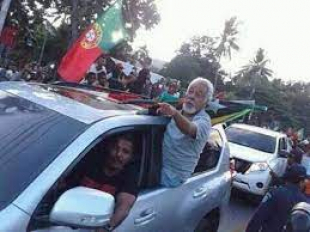 Lider Krismatiku Kay Rala Xanana Gusmăo iha hela kareta leten ho bandeira portugal halo komboiu iha dili laran momentu balun liu-ba.