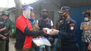 Segundu Komandante PNTL munisipiu Dili, Superintendente Polísia, Euclides da Costa Belo entrega hela máskra &quot;face protection&quot; ba komunidade mane ida iha merkadu munisipal Taibessi, kuarta (17/03). 